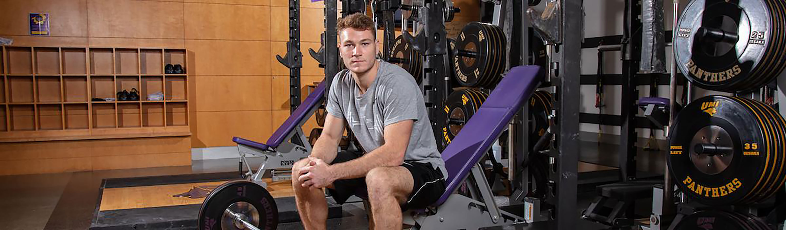 Student sitting on a bench exercise equipment.