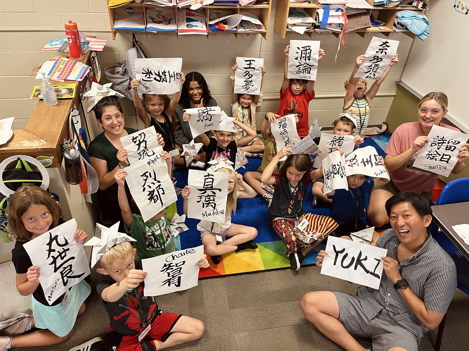 Students at Cedar Valley Preschool holding up their names writing in Japanese as done by CEIP Student Yuki Kanda