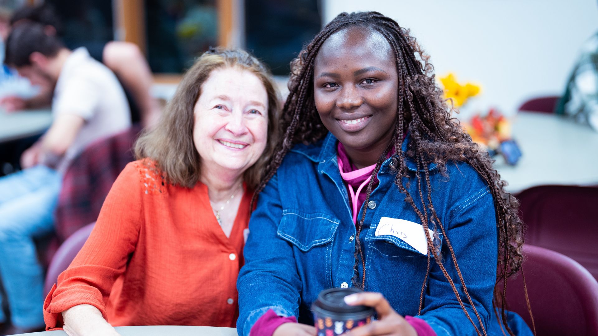 On the Left is Fayth, a Family Friendship Program Volunteer wearing a red shirt, and on the right is a student in the Family Friendship Program wearing a Blue Denim Jacket