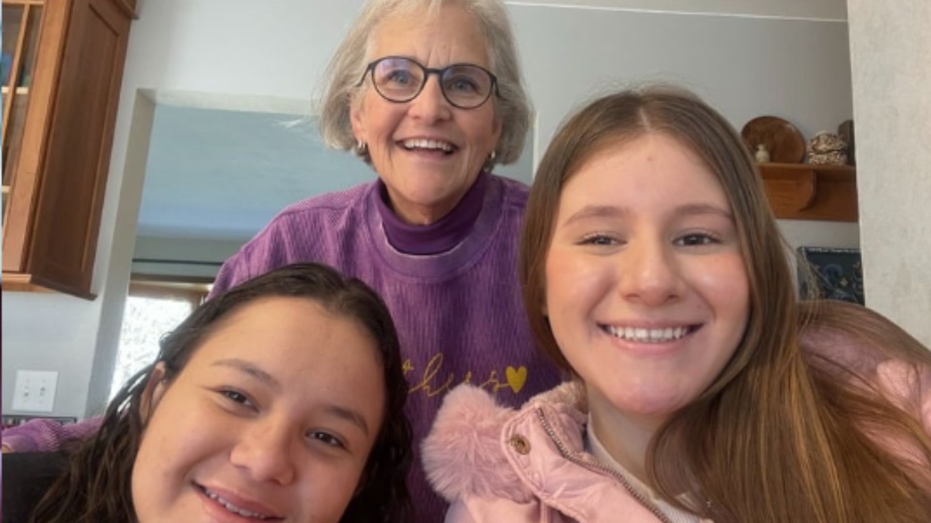 Family Friendship Program Volunteer Moira in the back wearing Purple, and two student in the front taking a selfie