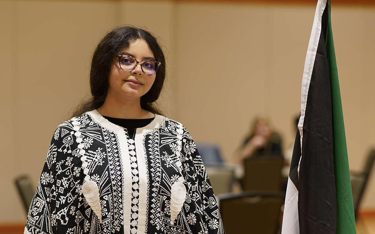 Female international student standing by her country's flag